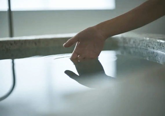 掛け流し上質なプライベートサウナ超軟水の水風呂をたしかめている女性の手