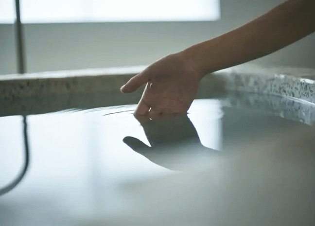 掛け流し上質なプライベートサウナ超軟水の水風呂をたしかめている女性の手