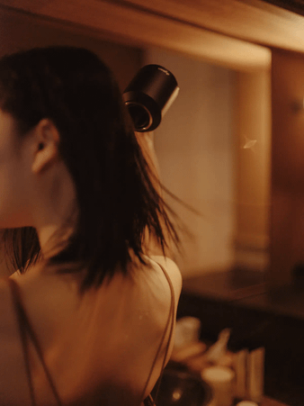 Dysonドライヤーで髪をかわす女性