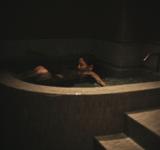 プライベートサウナルームの水深深い超軟水の水風呂につかる女性